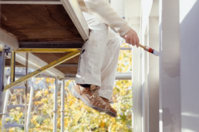 Man sitting on scaffolding, painting, low section